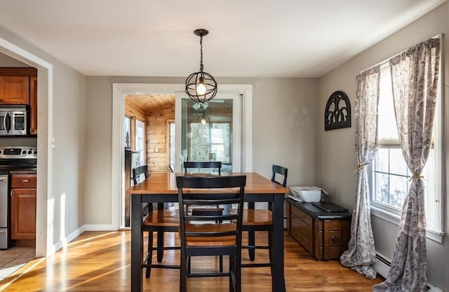 dining room featuring light wood-style floors, a wealth of natural light, and a baseboard radiator