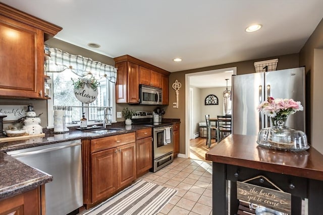 kitchen with brown cabinets, stainless steel appliances, recessed lighting, light tile patterned flooring, and a sink