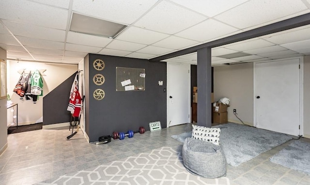 finished below grade area featuring a paneled ceiling and baseboards