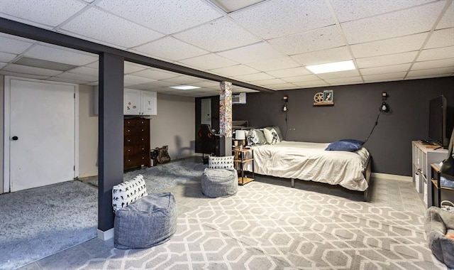 bedroom with a drop ceiling, light carpet, and baseboards