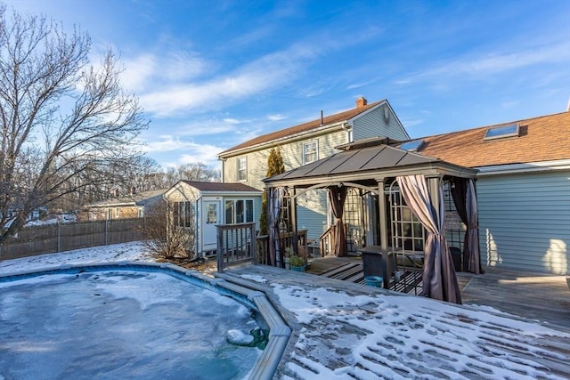 snow covered rear of property featuring fence and an outdoor structure