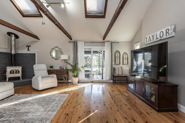 unfurnished living room with a wood stove, vaulted ceiling with beams, and wood finished floors