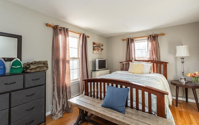 bedroom featuring light wood-type flooring, a baseboard radiator, and baseboards