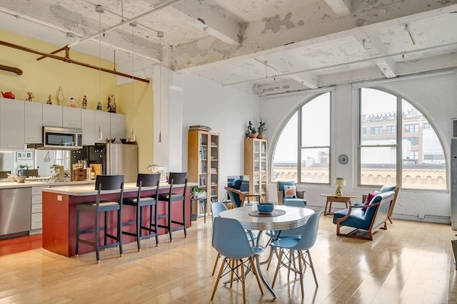 dining room with light wood-type flooring and a towering ceiling