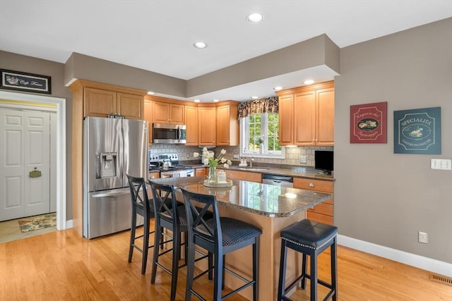 356 Grafton St, Shrewsbury, MA 01545 - kitchen with stainless steel appliances, a breakfast bar area, decorative backsplash, light wood-type flooring, and recessed lighting