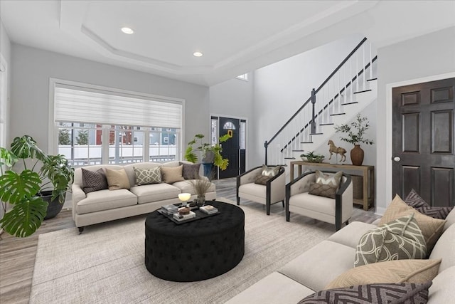 living room with a raised ceiling and light wood-type flooring