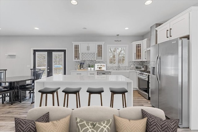 kitchen with backsplash, stainless steel appliances, white cabinetry, and a kitchen island