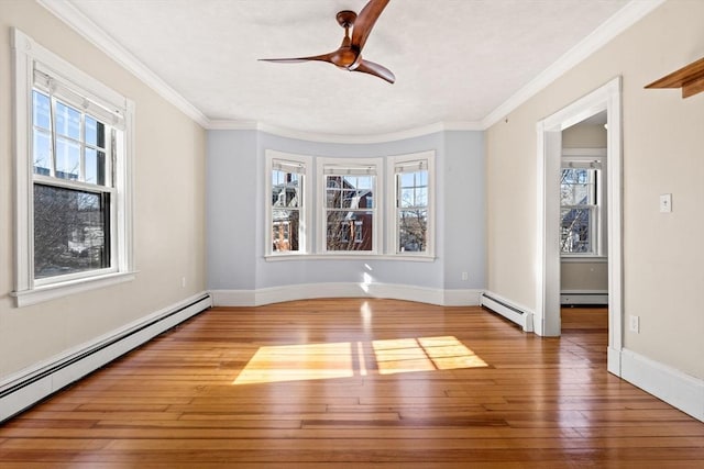 unfurnished room featuring hardwood / wood-style flooring, a baseboard heating unit, and a wealth of natural light