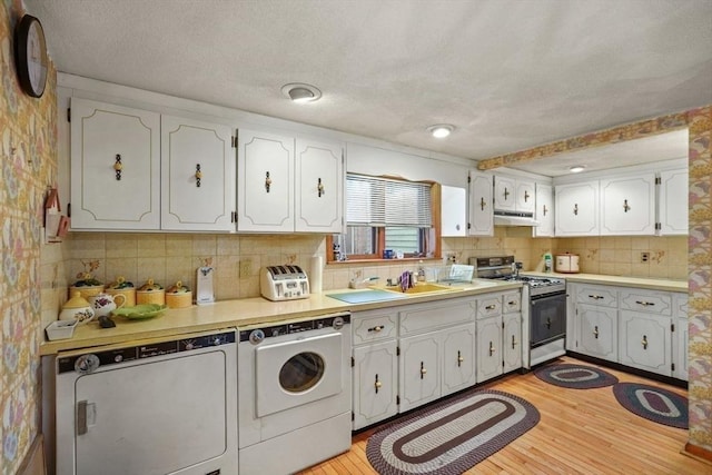 kitchen with light hardwood / wood-style flooring, white range with gas stovetop, backsplash, sink, and white cabinetry