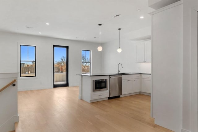 kitchen featuring stainless steel dishwasher, white cabinets, kitchen peninsula, and sink