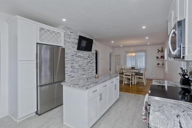 kitchen with pendant lighting, light hardwood / wood-style flooring, appliances with stainless steel finishes, light stone counters, and white cabinetry