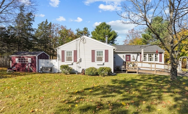 rear view of property featuring a storage shed, a lawn, and a deck