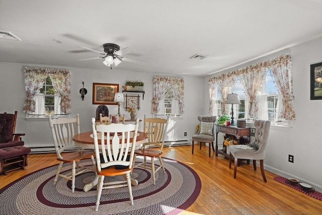 dining space with baseboard heating, a wealth of natural light, light hardwood / wood-style floors, and ceiling fan