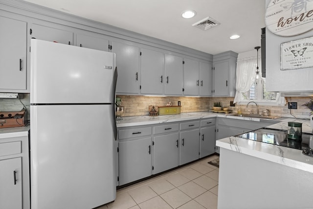 kitchen with white refrigerator, decorative light fixtures, light tile patterned floors, gray cabinets, and decorative backsplash