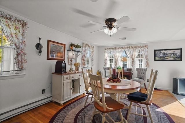 dining space featuring ceiling fan, light hardwood / wood-style floors, baseboard heating, and a healthy amount of sunlight