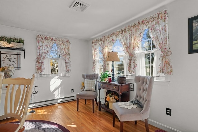 sitting room with hardwood / wood-style flooring and a baseboard heating unit