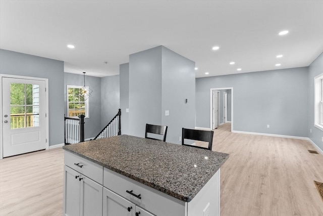 67 Elliott Ave, Dracut, MA 01826 - kitchen with light wood-style flooring, a center island, dark stone counters, white cabinets, and recessed lighting