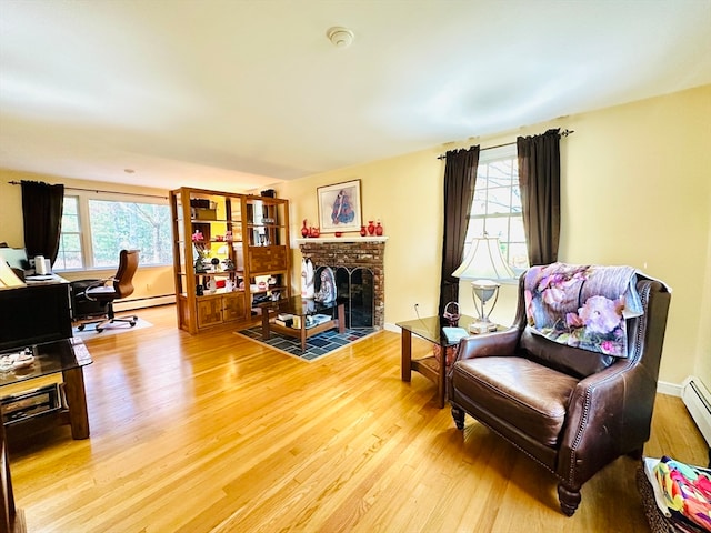 sitting room featuring a fireplace, wood-type flooring, and a baseboard heating unit