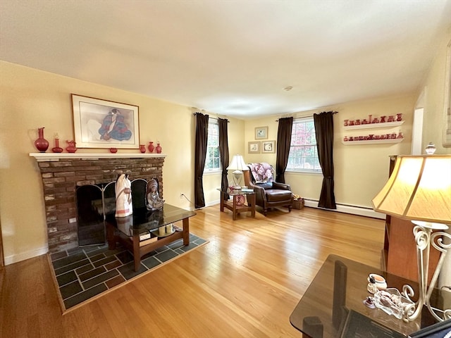 living room with hardwood / wood-style floors, a brick fireplace, and baseboard heating