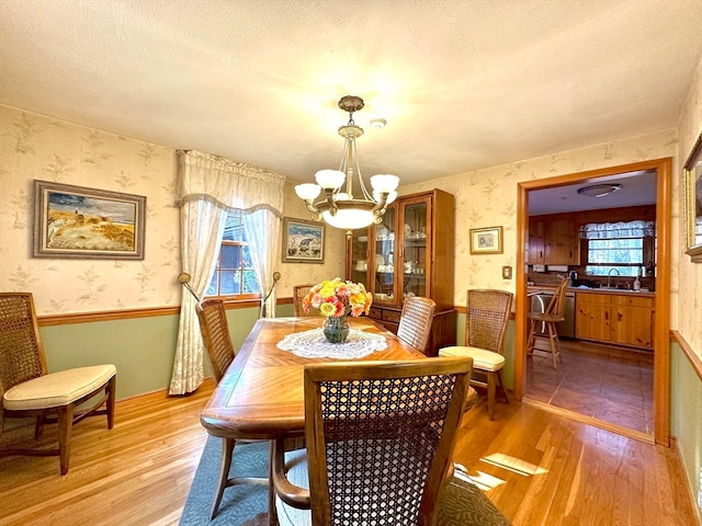 dining area with a chandelier, sink, a textured ceiling, and light hardwood / wood-style flooring