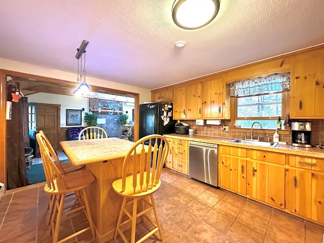 kitchen with tasteful backsplash, stainless steel dishwasher, hanging light fixtures, and sink