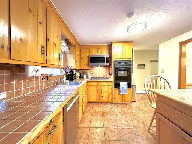 kitchen featuring backsplash, a textured ceiling, stainless steel appliances, sink, and tile counters