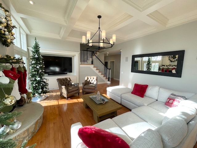 living room with coffered ceiling, beamed ceiling, a notable chandelier, wood-type flooring, and ornamental molding