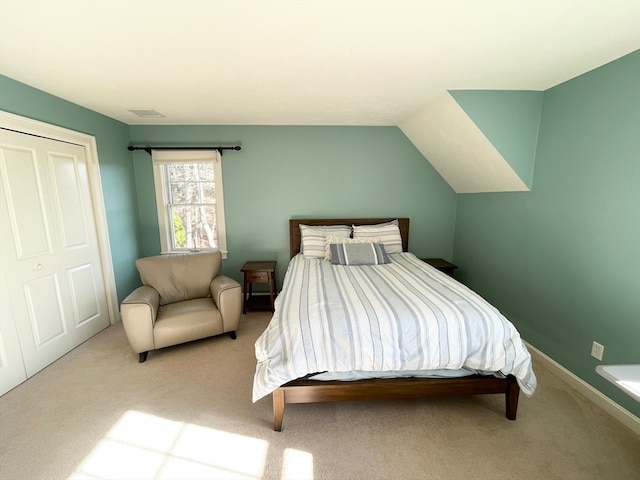 bedroom with vaulted ceiling, light carpet, and a closet