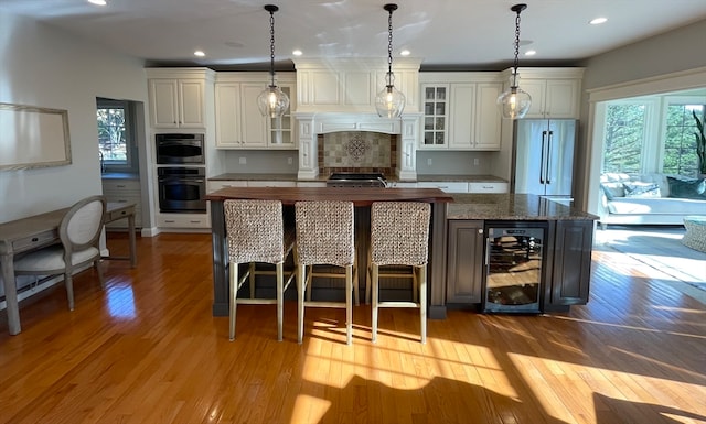 kitchen featuring wine cooler, a kitchen island, stainless steel appliances, and decorative light fixtures