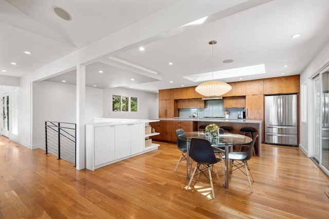 dining room featuring light wood-style flooring, recessed lighting, a skylight, and baseboards