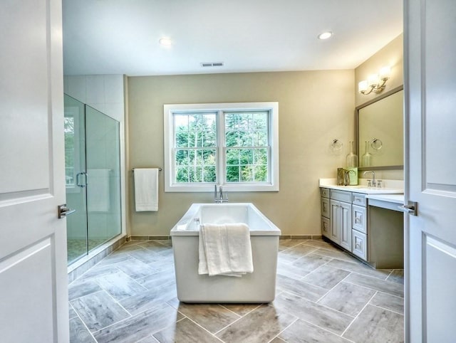 bathroom featuring vanity, a stall shower, a freestanding tub, baseboards, and recessed lighting