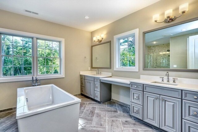 full bath with vanity, a stall shower, baseboards, and a freestanding tub
