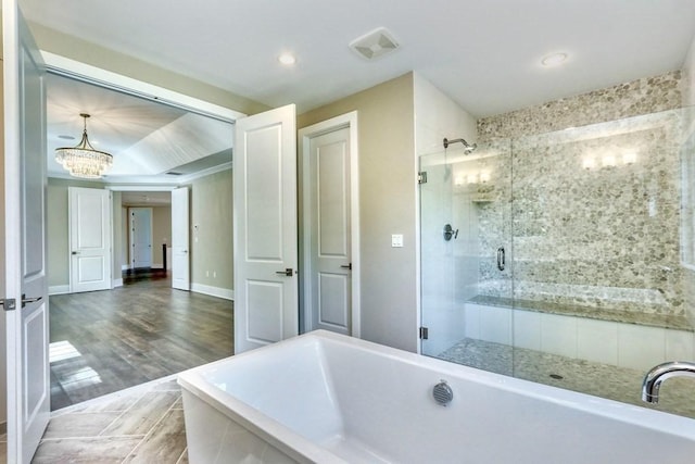 full bathroom featuring a chandelier, a shower stall, a freestanding tub, recessed lighting, and wood finished floors