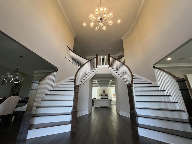 staircase featuring a chandelier, a high ceiling, ornamental molding, wood finished floors, and baseboards