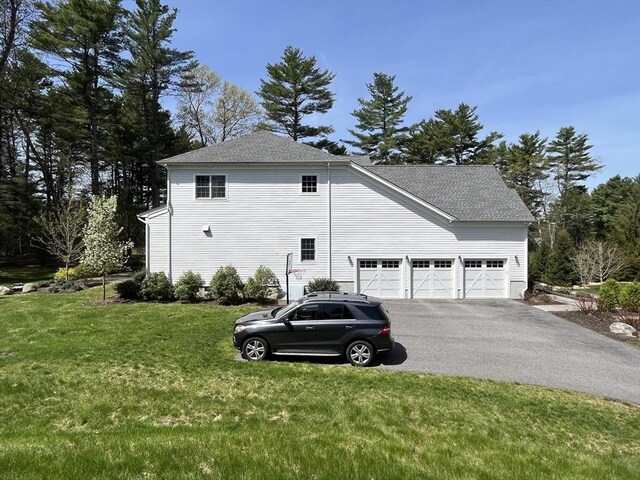 view of home's exterior featuring asphalt driveway, a lawn, roof with shingles, and an attached garage