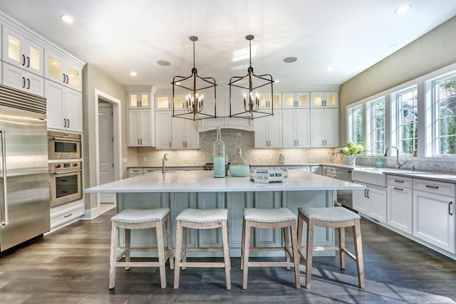 kitchen with appliances with stainless steel finishes, an island with sink, tasteful backsplash, a sink, and recessed lighting
