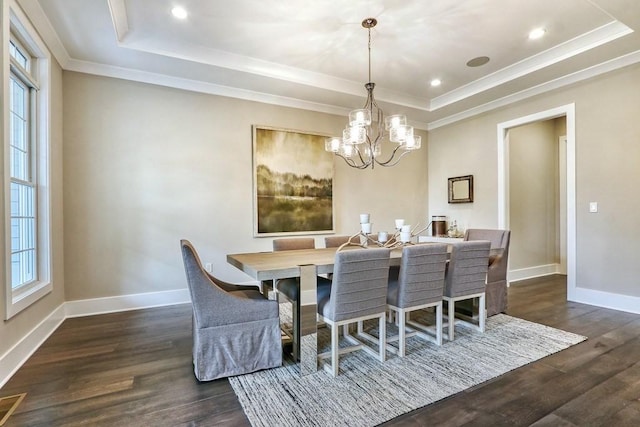 dining area featuring a raised ceiling, a chandelier, dark wood-style flooring, baseboards, and ornamental molding