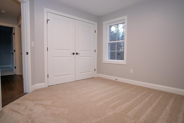 unfurnished bedroom with light colored carpet and a closet