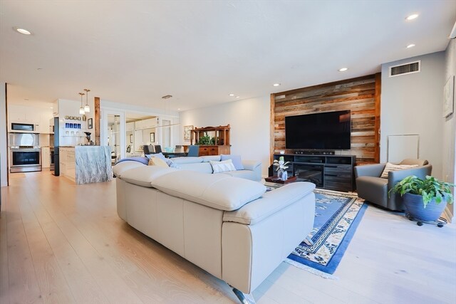 living room featuring wooden walls and light hardwood / wood-style flooring