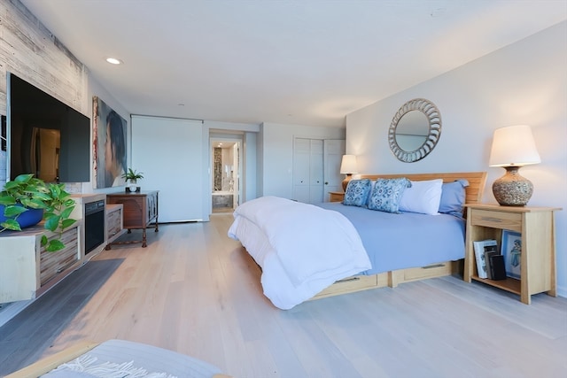 bedroom with ensuite bath, a closet, and light hardwood / wood-style flooring