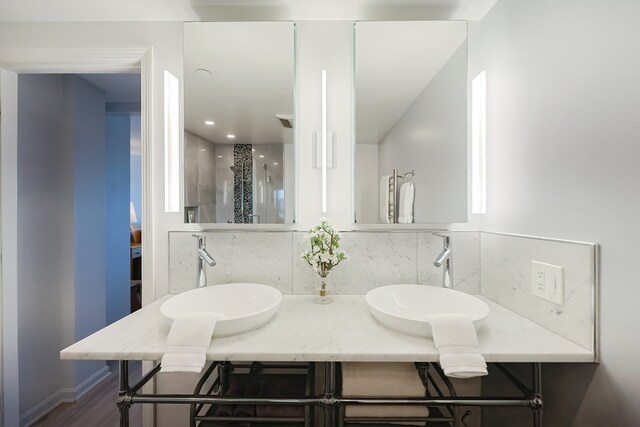 bathroom with decorative backsplash, a shower with door, hardwood / wood-style flooring, and vanity