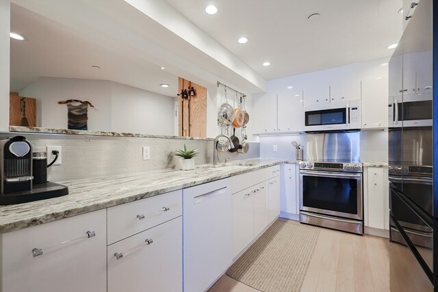 kitchen featuring light stone counters, white cabinets, white appliances, light hardwood / wood-style floors, and backsplash