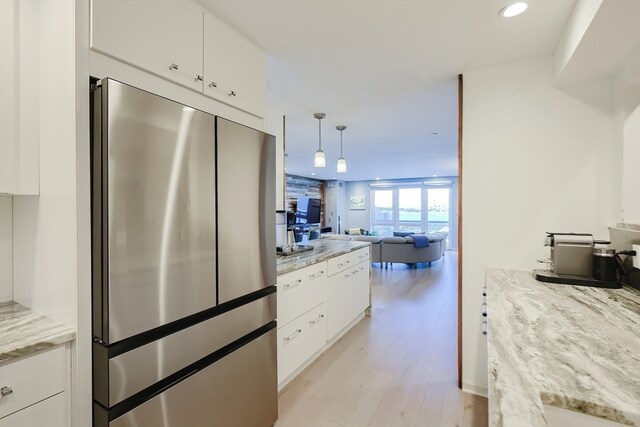 kitchen featuring pendant lighting, stainless steel fridge, light hardwood / wood-style floors, and white cabinetry