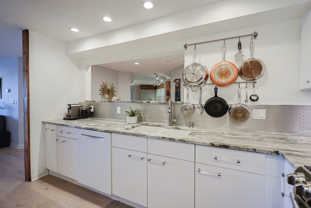 kitchen with white cabinets, light hardwood / wood-style floors, and sink