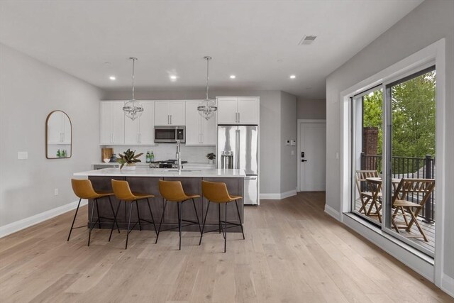 kitchen featuring a center island with sink, a breakfast bar, light wood-type flooring, and appliances with stainless steel finishes