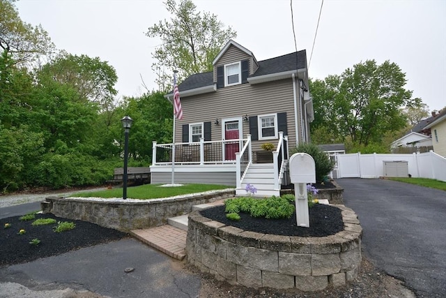 view of front of house featuring fence, asphalt driveway, a shingled roof, and a deck