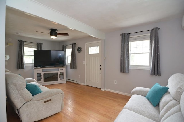 living area featuring a baseboard heating unit, baseboards, light wood-type flooring, and ceiling fan