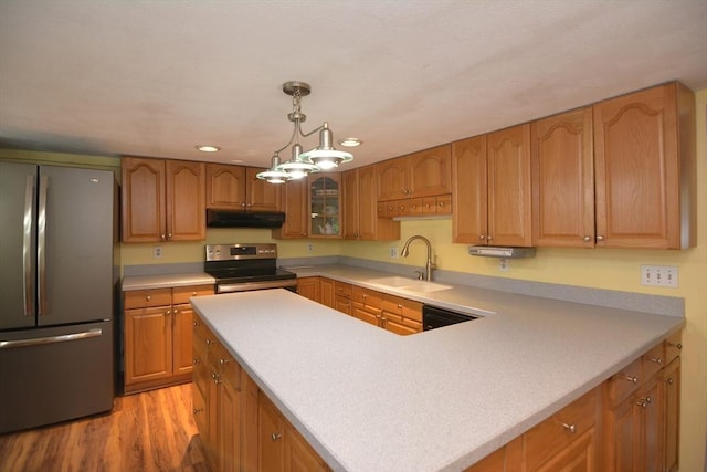 kitchen with stainless steel appliances, under cabinet range hood, a sink, light wood-type flooring, and light countertops