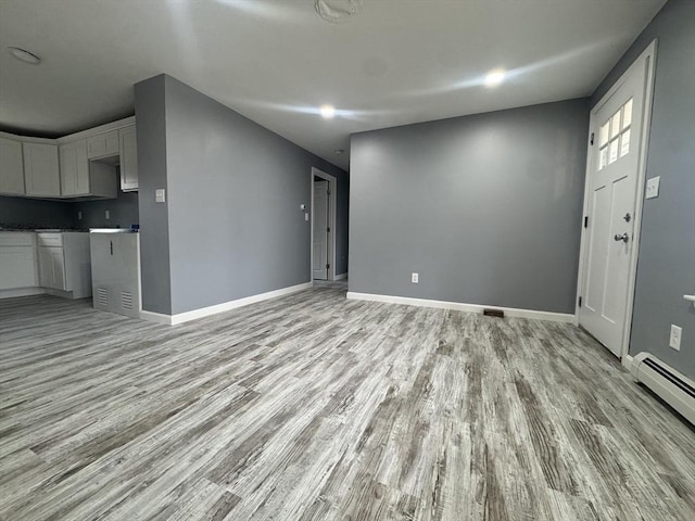 unfurnished living room featuring a baseboard radiator, light wood-style flooring, and baseboards