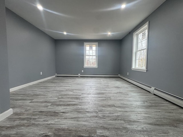 empty room with a baseboard radiator, recessed lighting, a baseboard heating unit, wood finished floors, and baseboards